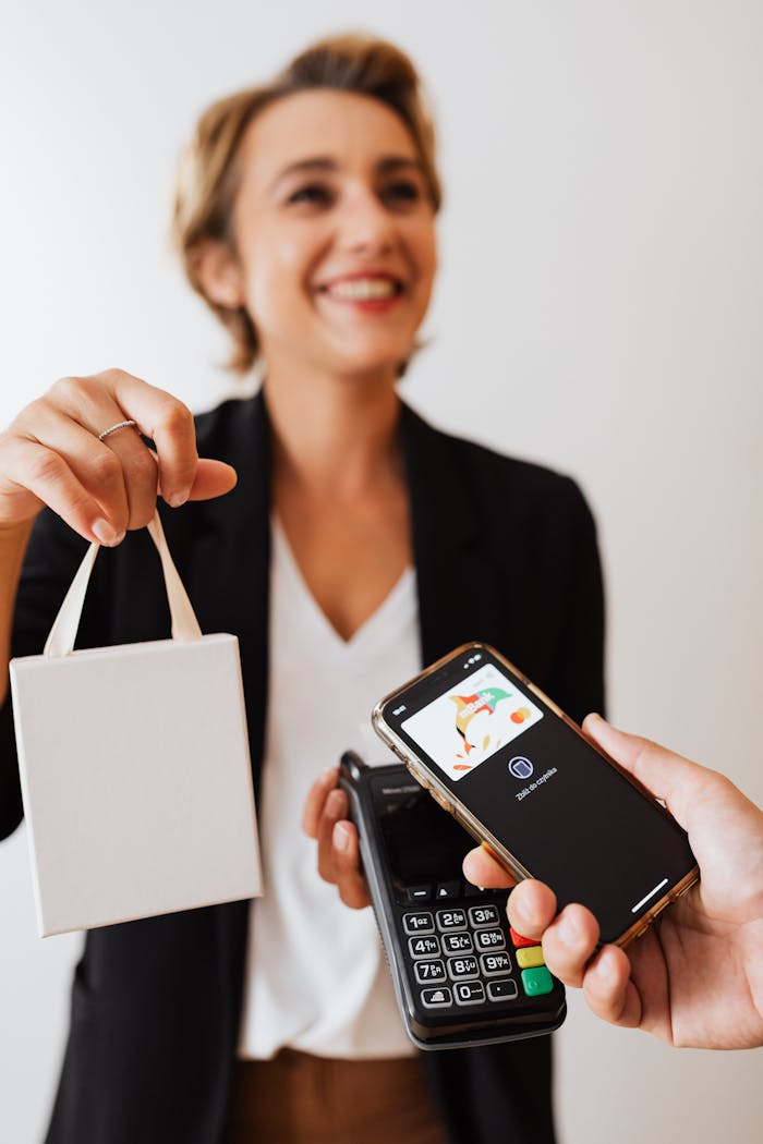 A woman uses a smartphone for contactless payment at a retail counter.